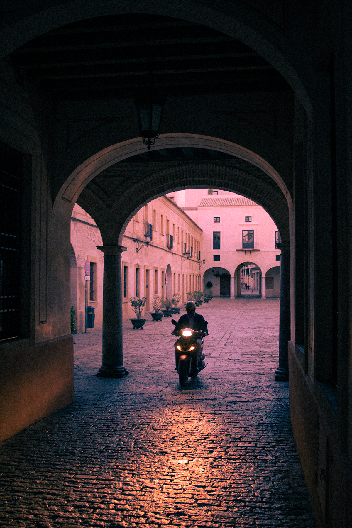 A motorcyclist rides past us on a stone road.